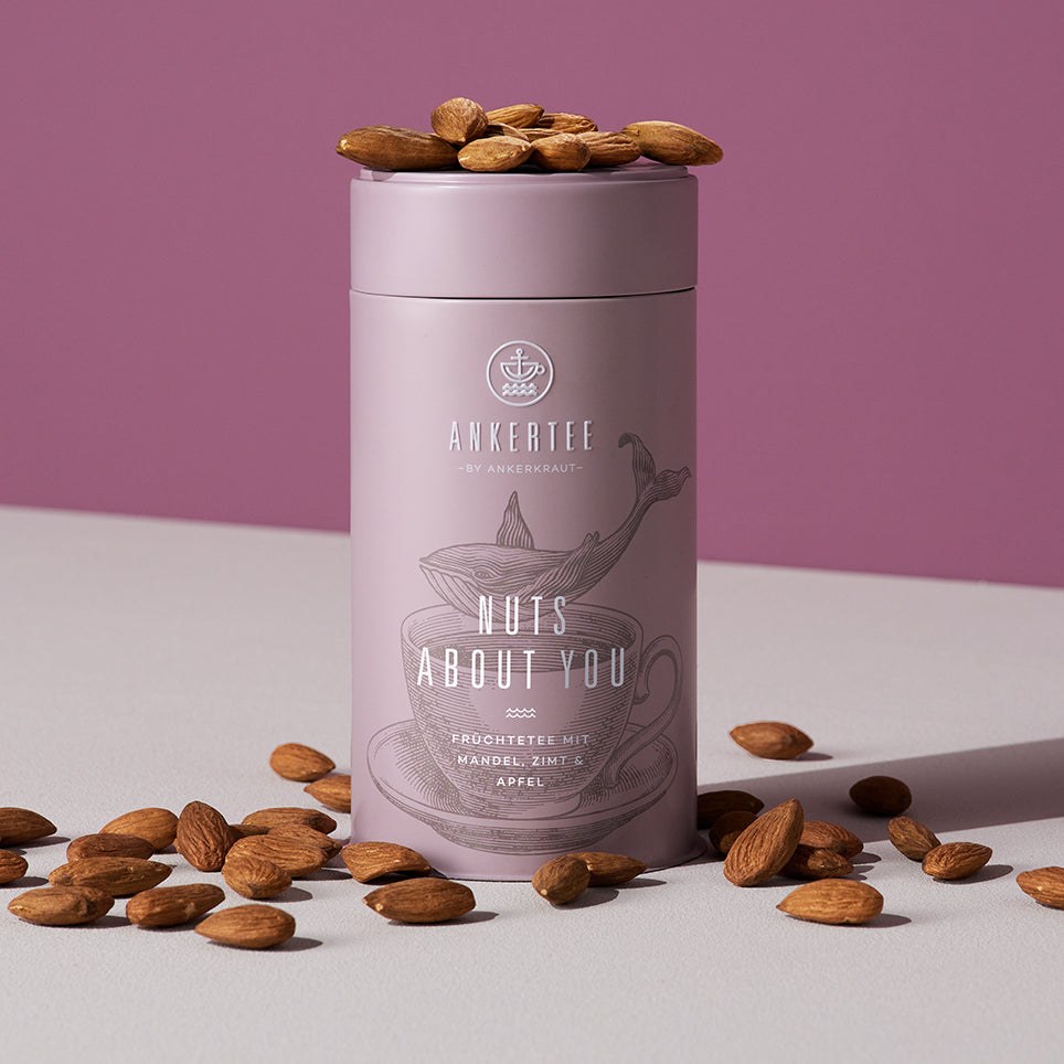 Eine Ankertee-Dose mit der Aufschrift NUTS ABOUT YOU, auf und neben der Dose liegen lose Mandeln